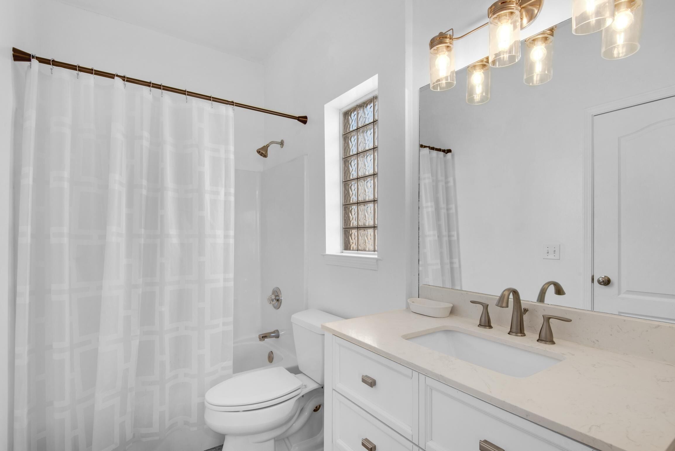 A bathroom with a toilet, sink, and shower curtain.