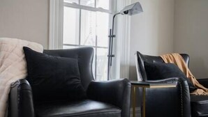 Una sala de estar moderna con un sofá de cuero negro, una mesita auxiliar y una lámpara de pie.