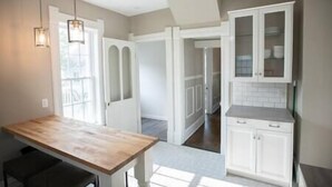 Una cocina con armarios blancos, encimera de madera e iluminación colgante.