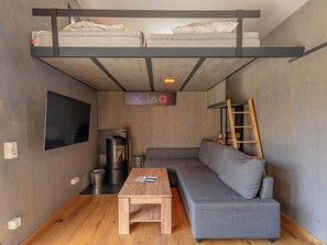 Um espaço compacto com beliche, sofá, televisão e uma pequena mesa.