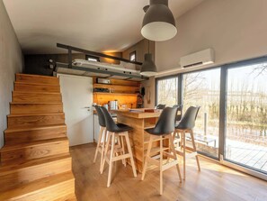 Uma cozinha moderna com piso de madeira, uma área de refeições com cadeiras e uma escada.