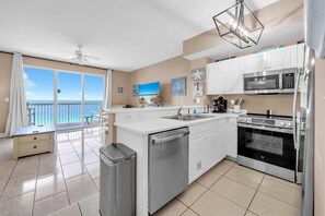 A modern kitchen with a view of the ocean, a dishwasher, a stove, and a microwave. - Celadon 1103 - Beach Paradise (Panama City Beach)