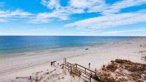 A beach with a wooden walkway leading to the shore, a clear sky, and calm sea. - The Sand Trap- Costa del Sol C-9 (Miramar Beach)