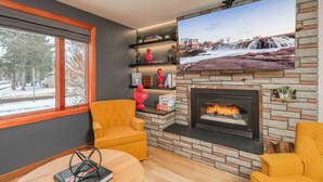 Una sala de estar acogedora con chimenea, un ventanal grande y una pared de piedra.