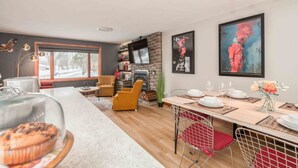 Una cocina moderna con una isla central, un comedor con mesa de madera y una chimenea.