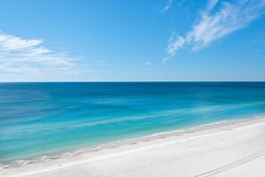 A beach with clear blue water and a sandy shore.