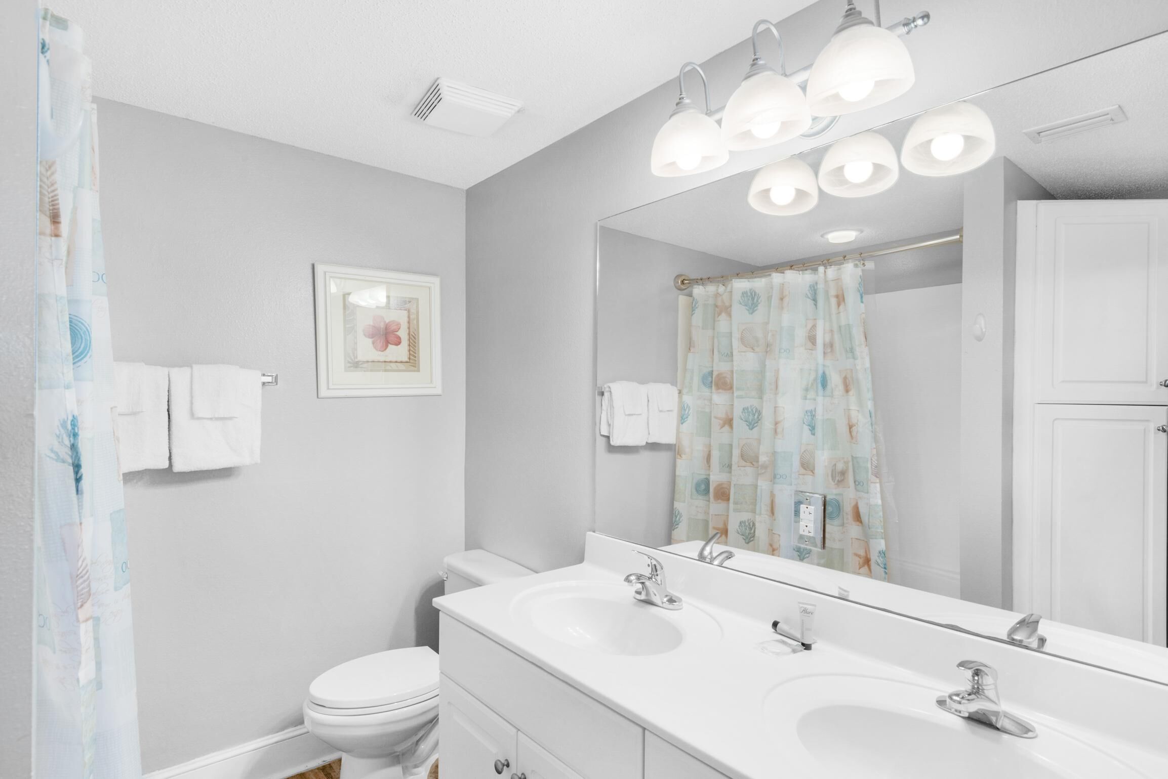 A bathroom with a white sink, two mirrors, and a shower curtain.