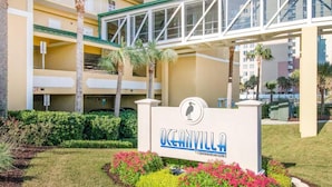 A sign for Oceanview Condominiums with a modern building in the background.