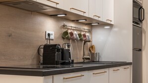 A modern kitchen with white cabinets, a black countertop, and a built-in espresso machine. - Upscale 3-room apartment, 300m from the beaches (Cannes)