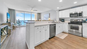 A modern kitchen with white cabinets, stainless steel appliances, and a view to the outside.