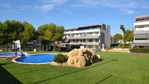 Un bâtiment moderne doté d’une piscine, entouré de pelouses et d’arbres bien entretenus.
