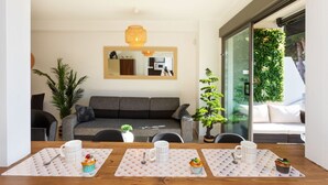 Un salon moderne avec un canapé, une table à manger avec des sets de table et un grand miroir au mur.