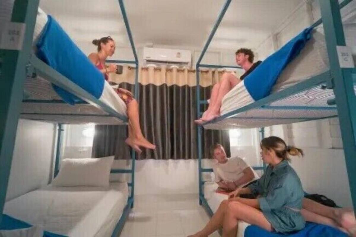 Quarto com beliche, uma janela e cortina.