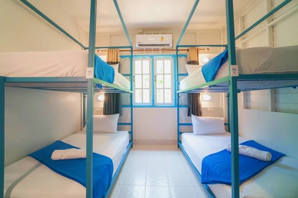 Um quarto com beliches, uma janela com cortinas e um ar condicionado.