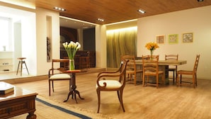 Een ruime woonkamer met houten vloer, een eethoek met houten meubels en een groot raam dat zorgt voor veel daglicht.