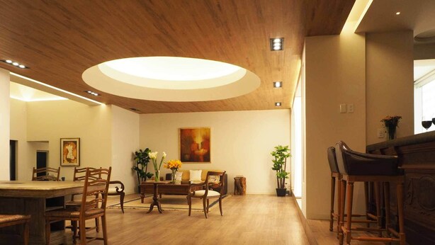 Een ruime eetruimte met houten meubels, een grote tafel en een moderne plafondlamp.