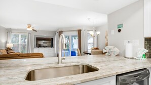 A modern kitchen with a stainless steel sink, white cabinets, and a dishwasher. - Hidden Dunes Beach Cottage 208- Dune Our Thing (Miramar Beach)