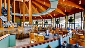 A spacious restaurant with wooden beams, large windows, and a central bar area. - Edgewater Golf Villa 3308 (Panama City Beach)