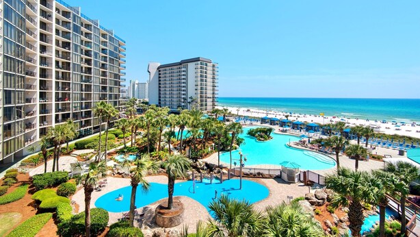 A resort with a large swimming pool, palm trees, and a beach view. - Edgewater Golf Villa 3308 (Panama City Beach)