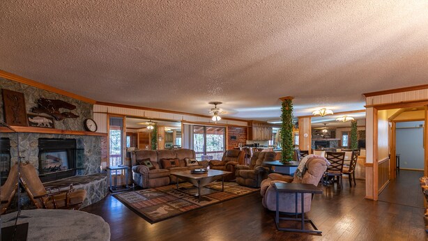 A spacious living room with a fireplace, leather sofas, a coffee table, and a large window.