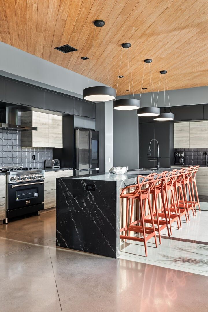 Une cuisine moderne dotée d’un îlot central, de tabourets de bar et d’appareils électroménagers en acier inoxydable.