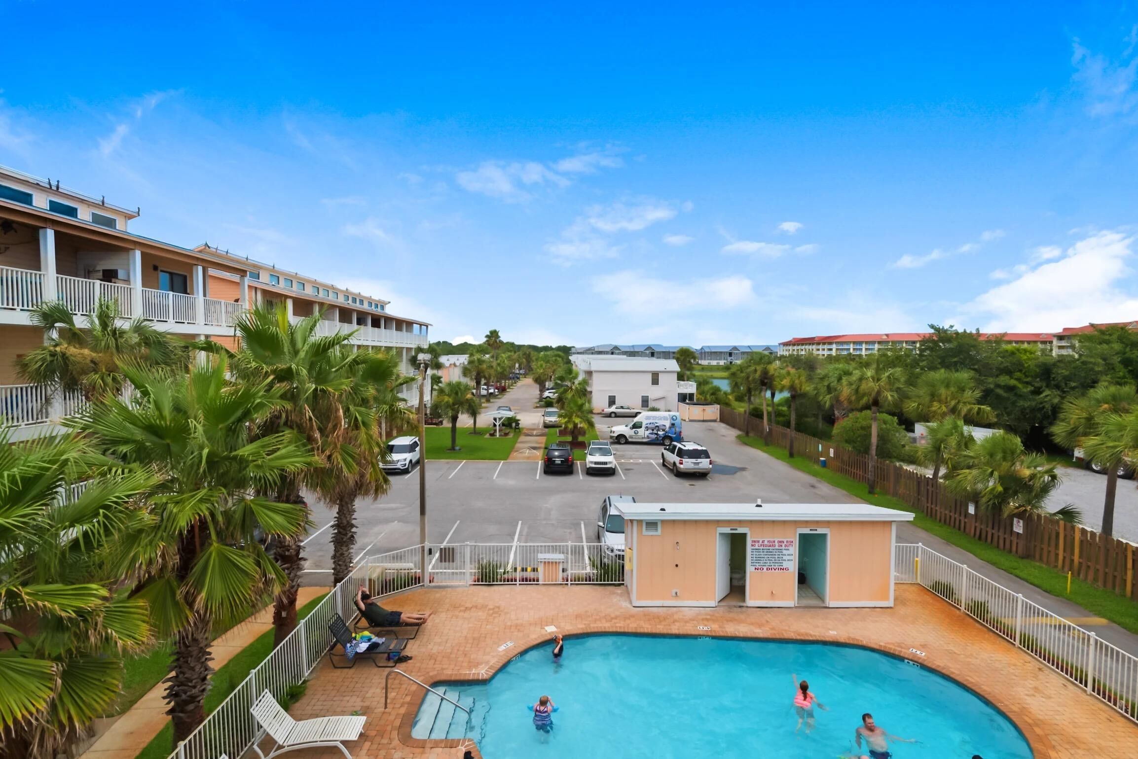Un hotel con piscina, palmeras y estacionamiento.