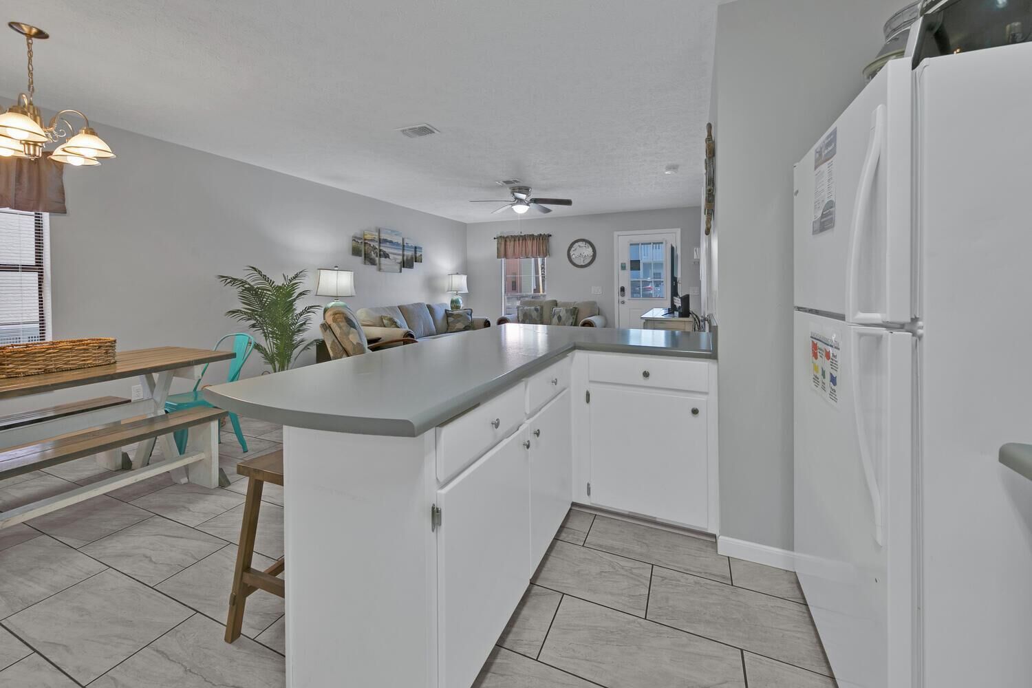 A compact kitchen with white cabinets, a central island, and a refrigerator.