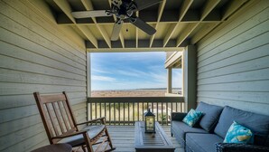 Une terrasse en bois avec un canapé, des fauteuils à bascule et une table.