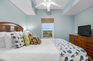 A bedroom with a bed, a television on a wooden dresser, and a window with a view. - Ariel Dunes I 606 (Miramar Beach)