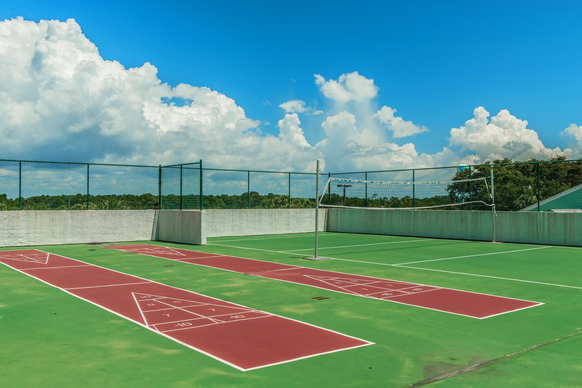 A tennis court with a net and a shuffleboard court.