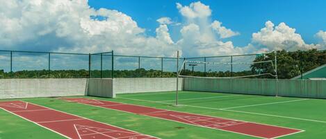 A tennis court with a net and a shuffleboard court.