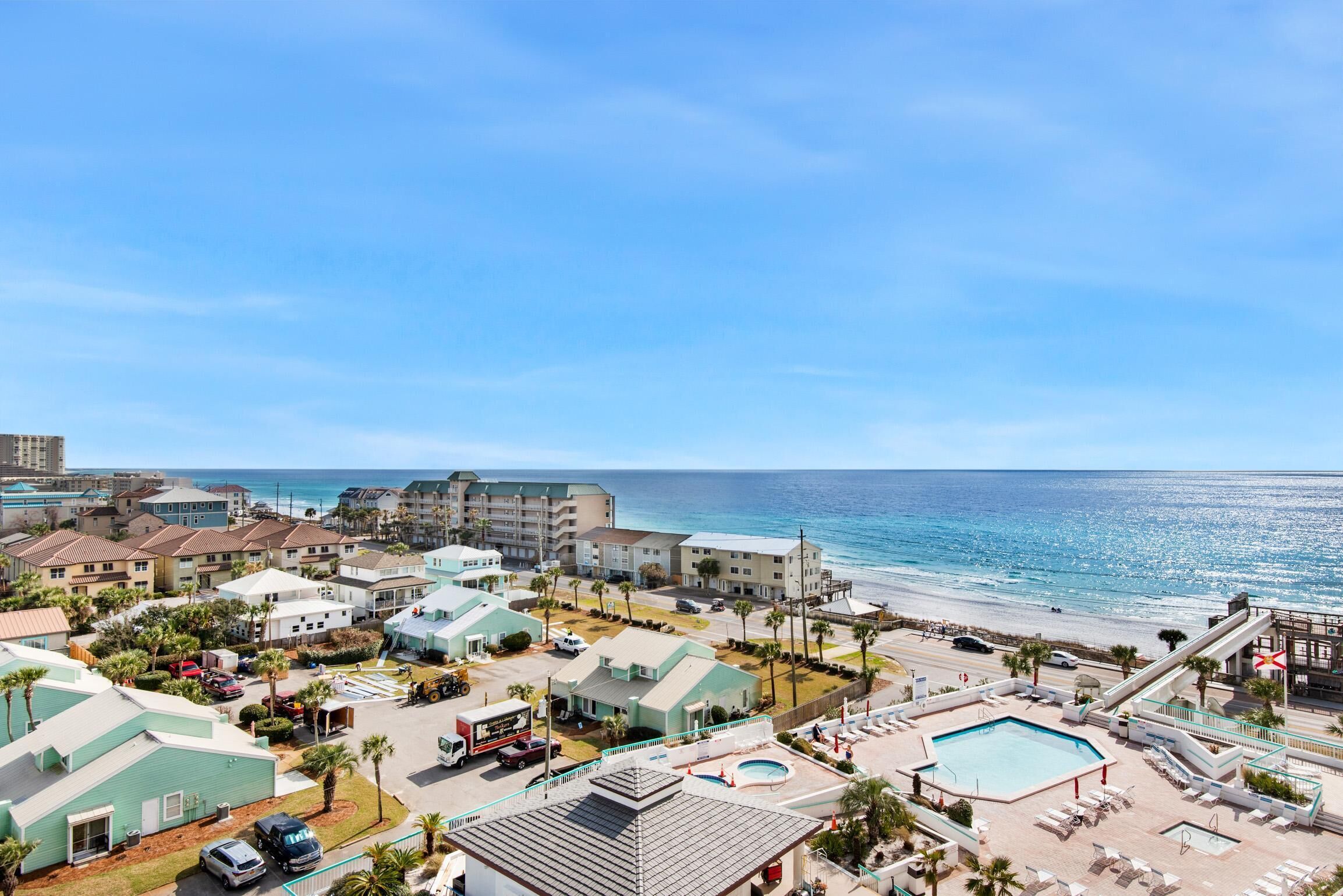A resort with multiple buildings, a swimming pool, and a beach view.