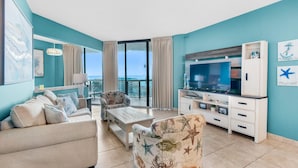 A living room with a sofa, armchair, coffee table, TV, and entertainment unit.