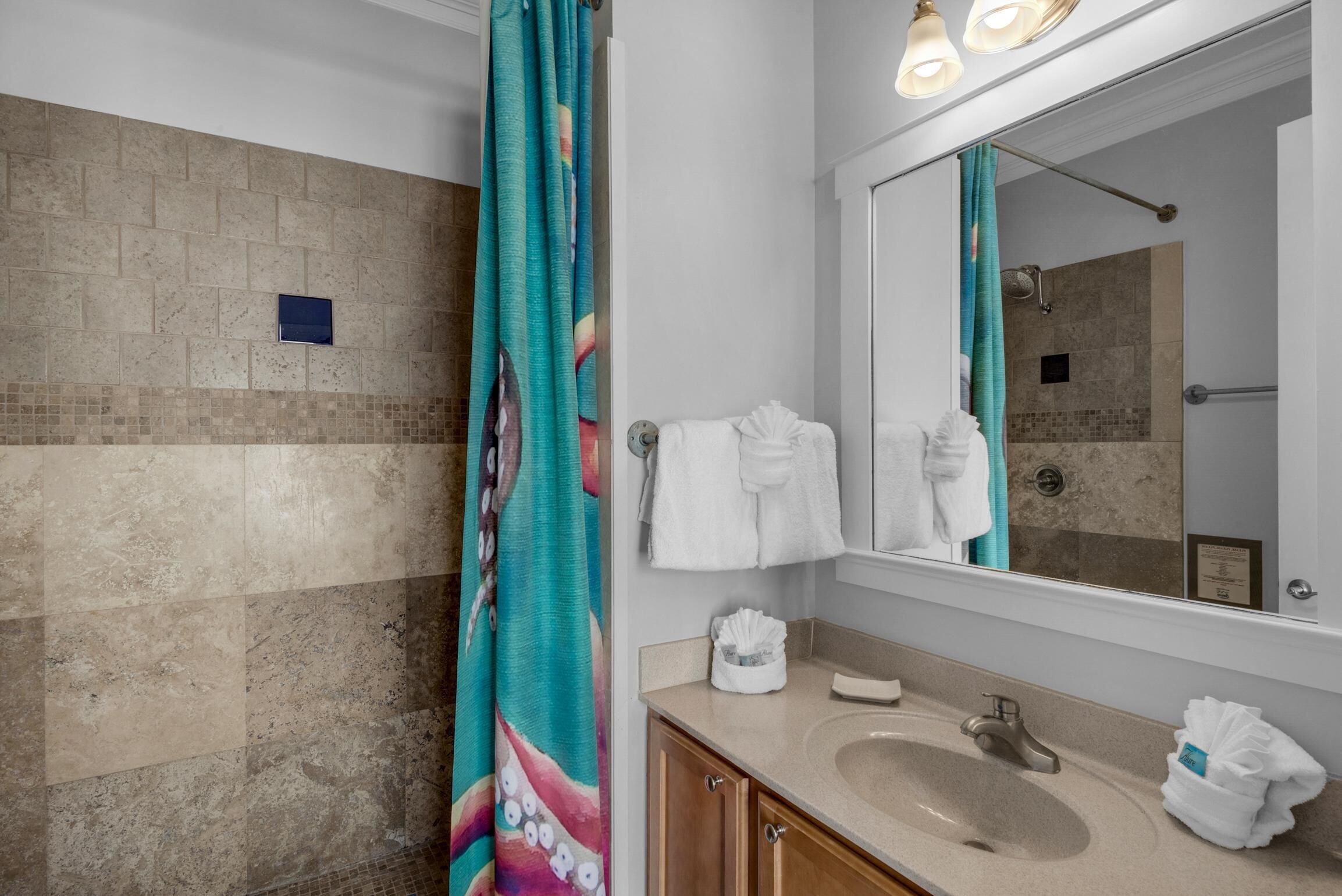 A bathroom with a beige sink, a mirror, and a shower curtain.