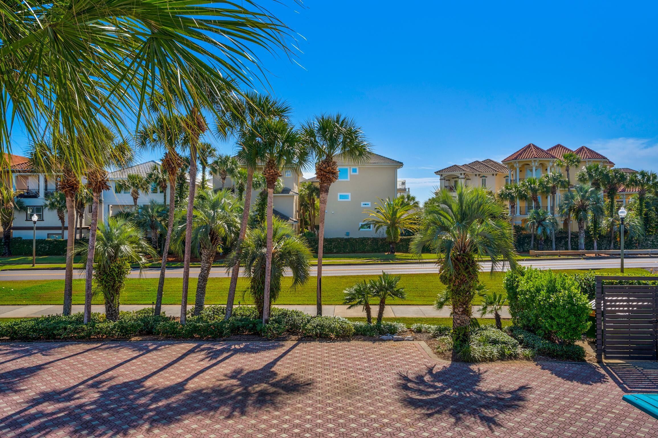 A hotel with multiple-story buildings, palm trees, and a paved walkway.