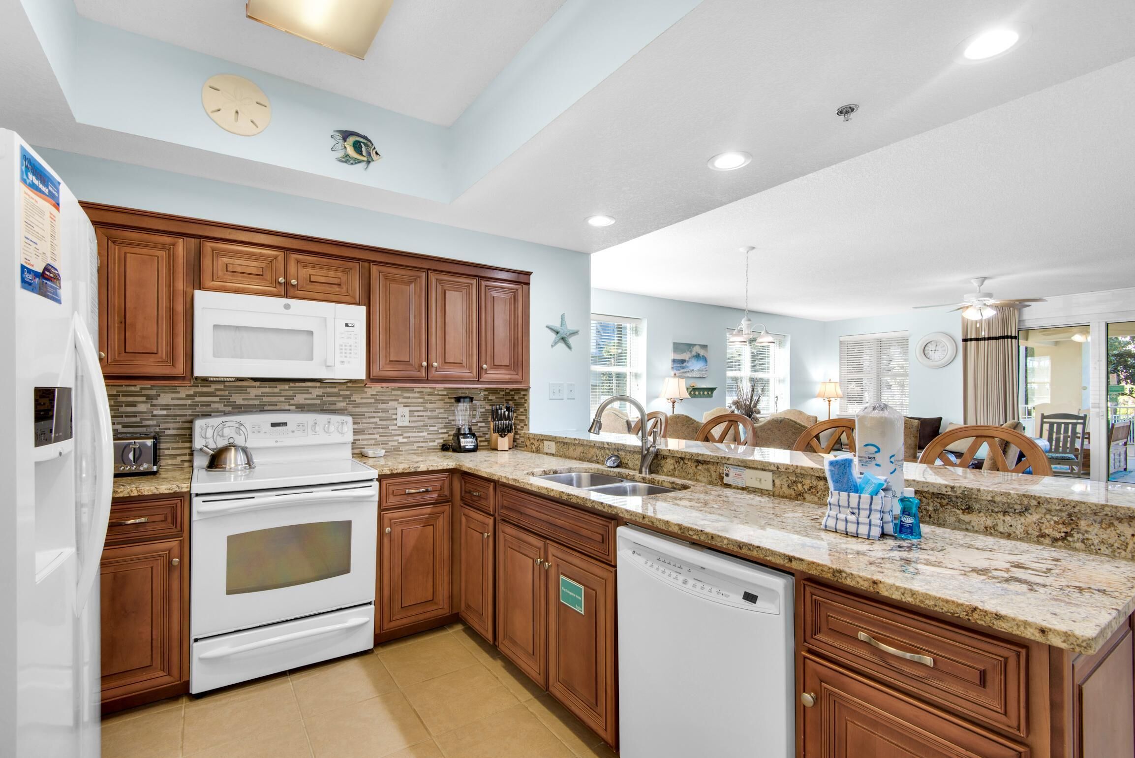 A modern kitchen with wooden cabinets, a white microwave, stove, and dishwasher.