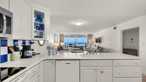 Una cocina moderna con armarios blancos, lavavajillas integrado y una isla grande con pileta.