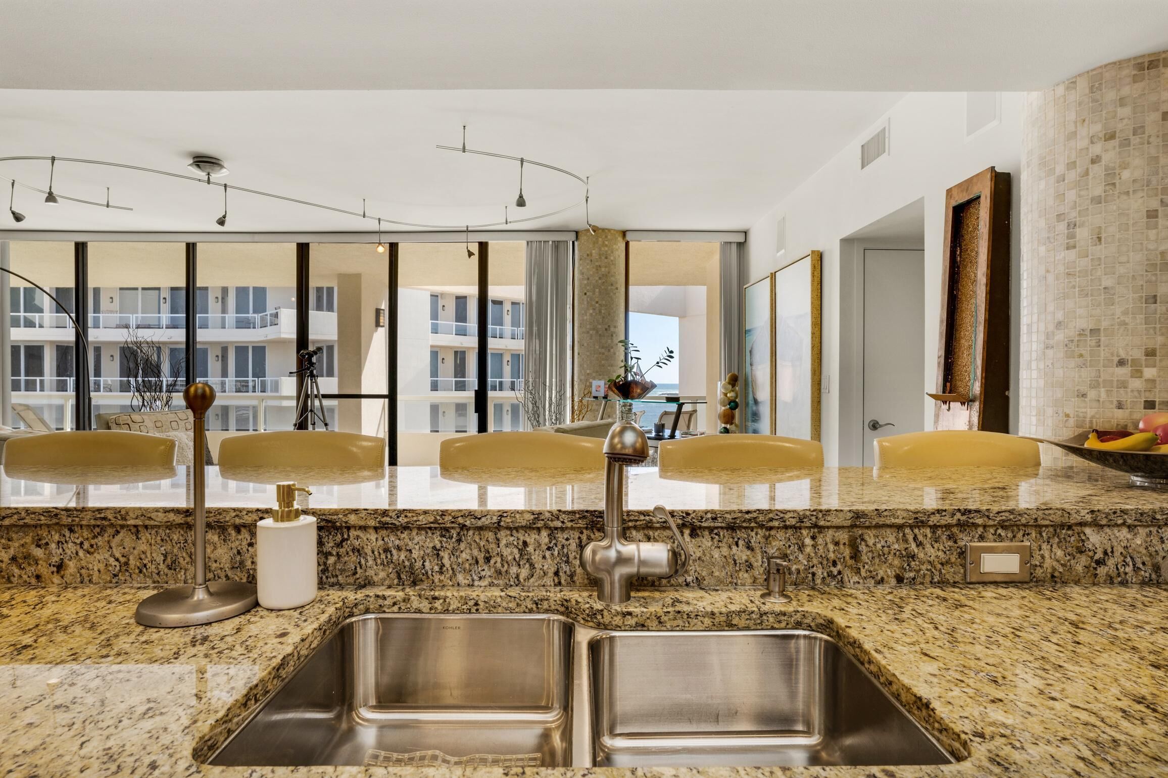 Une salle de bain moderne avec un comptoir en granit, deux lavabos et un grand miroir.