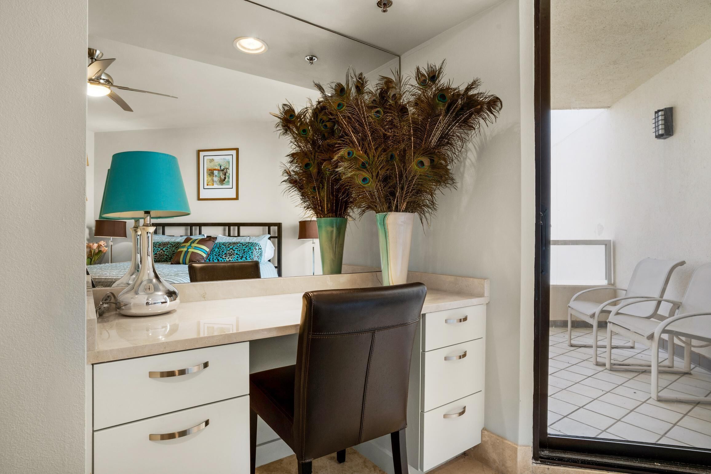 A modern bathroom with a white vanity, a black chair, and a large mirror.