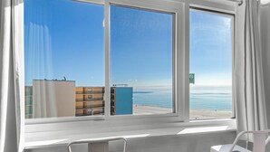 A room with a large window overlooking a beach and buildings. - Top of the Gulf 807 (Panama City Beach)