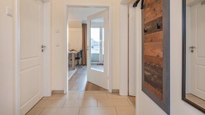 Un couloir avec des portes blanches, un mur d’accent en bois et une vue sur un coin repas.