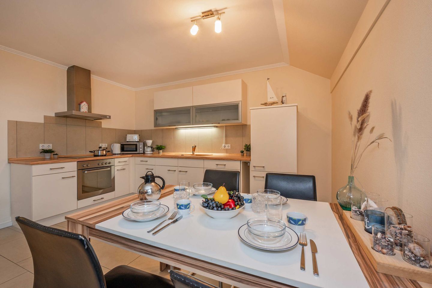 A modern kitchen with a dining area, equipped with a stove, oven, microwave, and a large window.