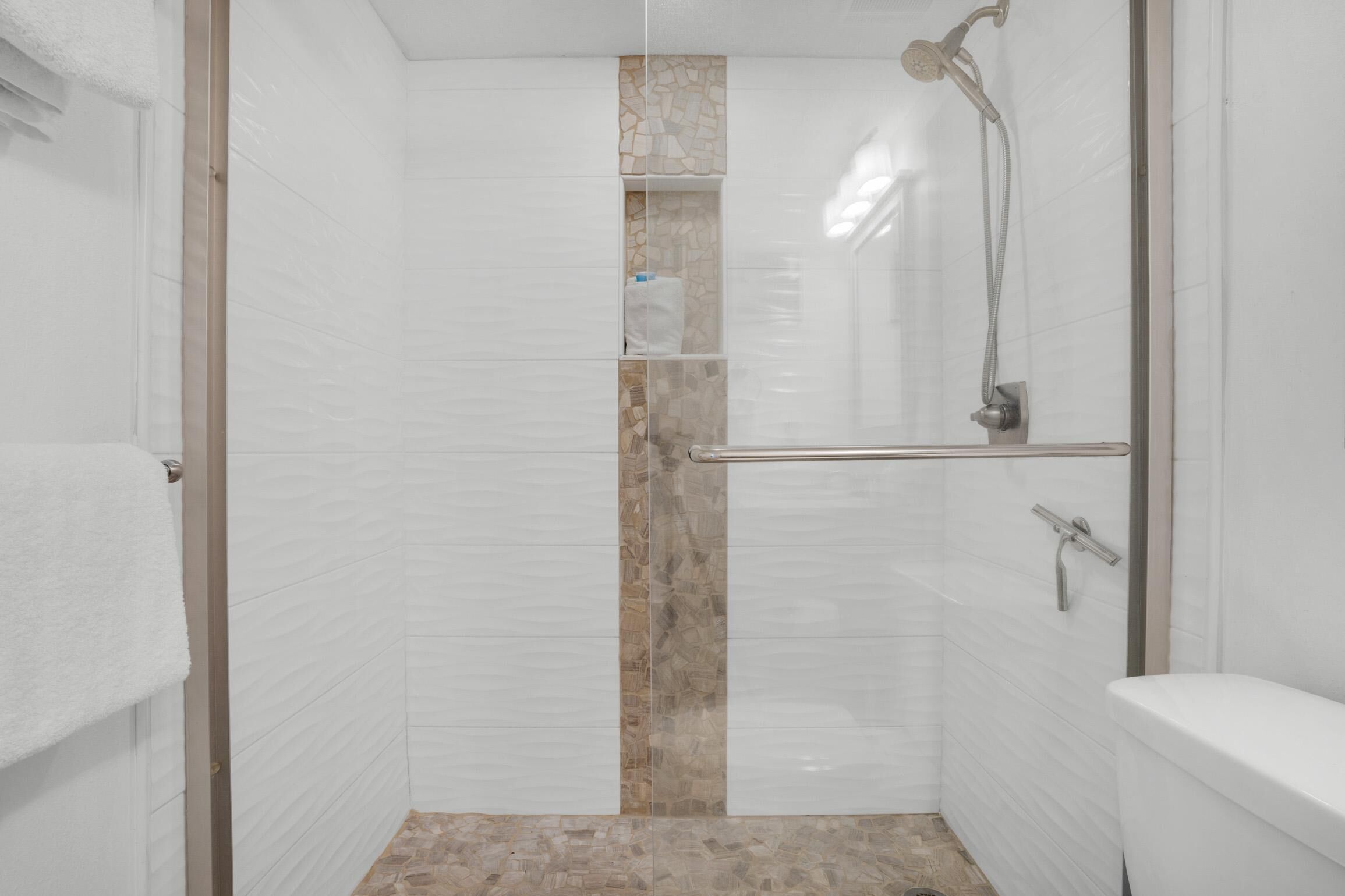 A bathroom with a shower, toilet, and a towel rack.