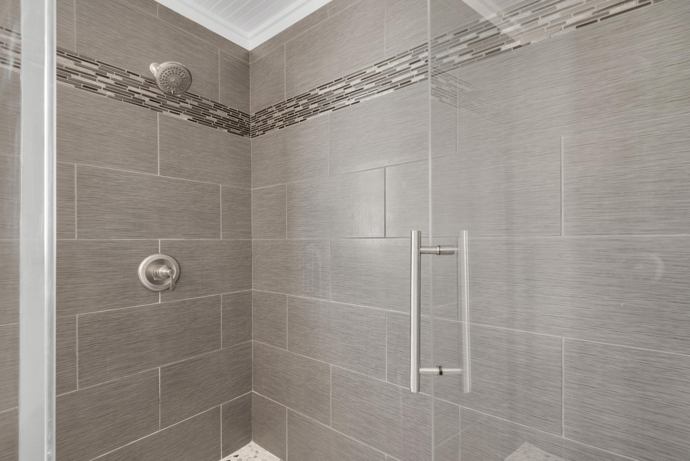 A modern shower with a rain showerhead and a wall-mounted control panel.
