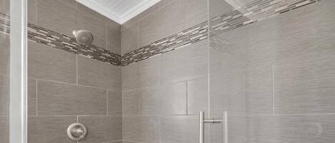 A modern shower with a rain showerhead and a wall-mounted control panel.
