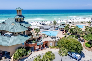 A resort with a pool, beach, and a building with a tower. - Bayside at Sandestin 6770 (Miramar Beach)