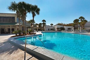 A swimming pool with a clear blue water, surrounded by palm trees and modern buildings. - Bayside at Sandestin 6770 (Miramar Beach)