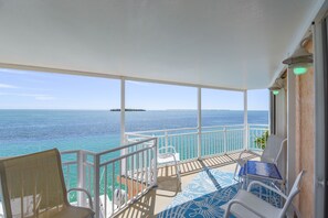 A balcony with a view of the ocean, white chairs, a table, and a patterned floor. - Slow M'Ocean #54 - Oceanfront Home - Cudjoe Key (Cudjoe Key)