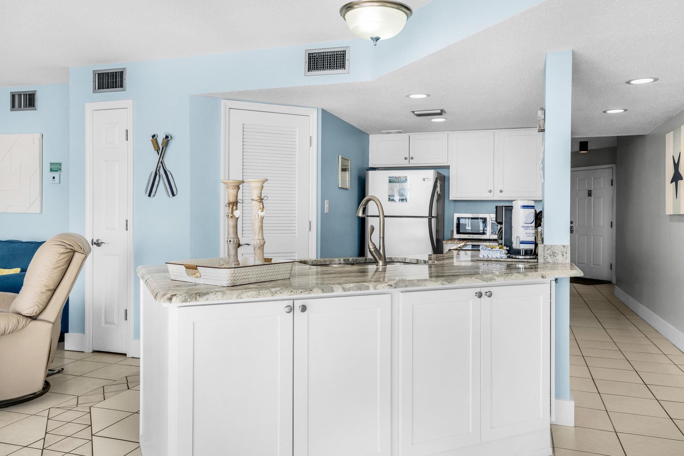A modern kitchen with white cabinets, a marble countertop, and stainless steel appliances.