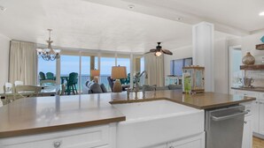 Una cocina moderna con una isla grande, armarios blancos y vista al océano.